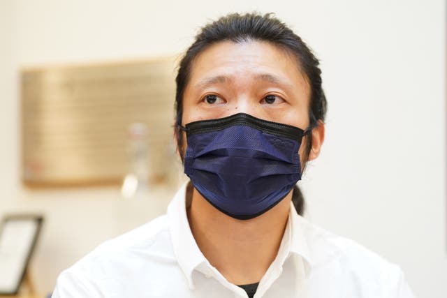 Bob Chan wearing a black face mask and a white shirt.