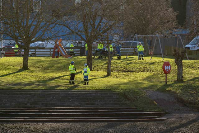 Police officers on a grass area beside a river