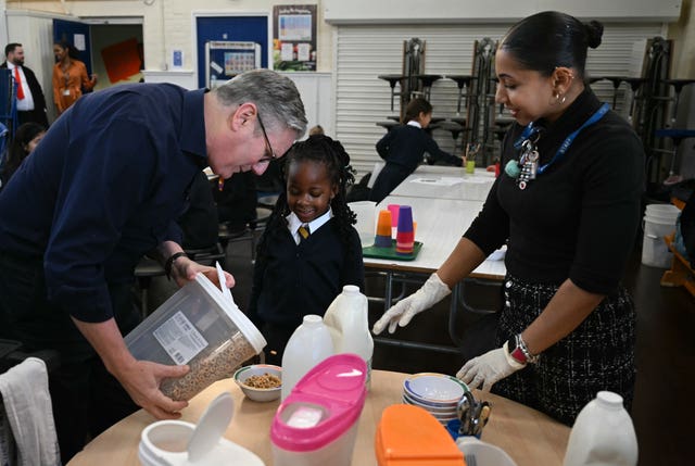 Prime Minister Sir Keir Starmer helps serve bowls of cereal to students 