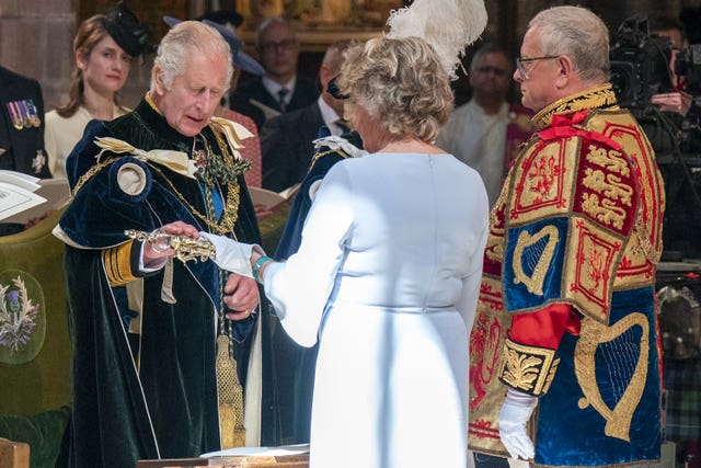 The King dressed in coronation robes accepting a Sceptre presented by Lady Dorrian, who is wearing a pale blue dress