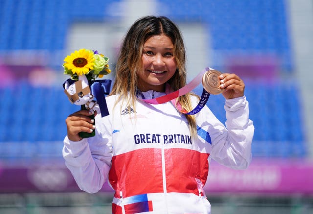 Sky Brown smiles while holding her bronze medal and flowers at the Tokyo Olympics