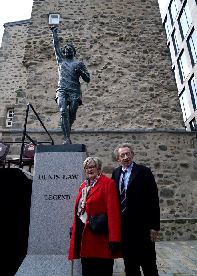 Denis Law and his wife Diana Law pose with his statue in Marischal Square, Aberdeen 
