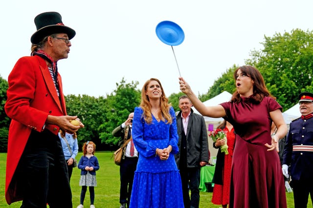 Princess Beatrice (centre) and Princess Eugenie trying their hand at plate spinning 