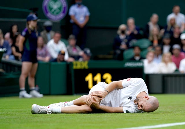 Adrian Mannarino holds his knee after slipping on Centre Court