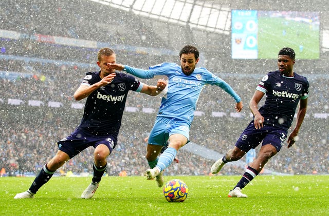 Manchester City's Bernardo Silva, centre, battles for possession with West Ham's Tomas Soucek, left, and Ben Johnsonin the snow
