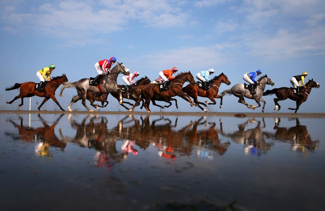 Runners and riders reflect in the water while competing in the Barry Matthews Appreciation Society Handicap during the 2014 Laytown Races held in County Meath Ireland. The historic race meeting, which takes place on a beach, was first held in 1868