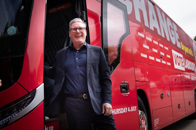 Sir Keir Starmer smiles as he steps off a red Labour battlebus