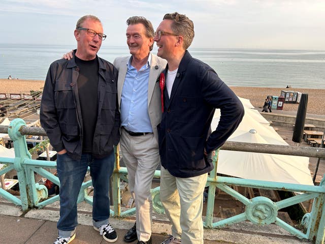 Three men standing in front of the beach at Brighton