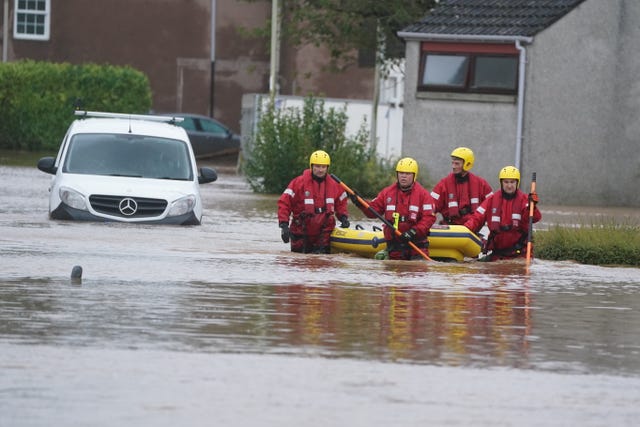 Members of a Coastguard rescue team wade through floodwaters in Brechin 