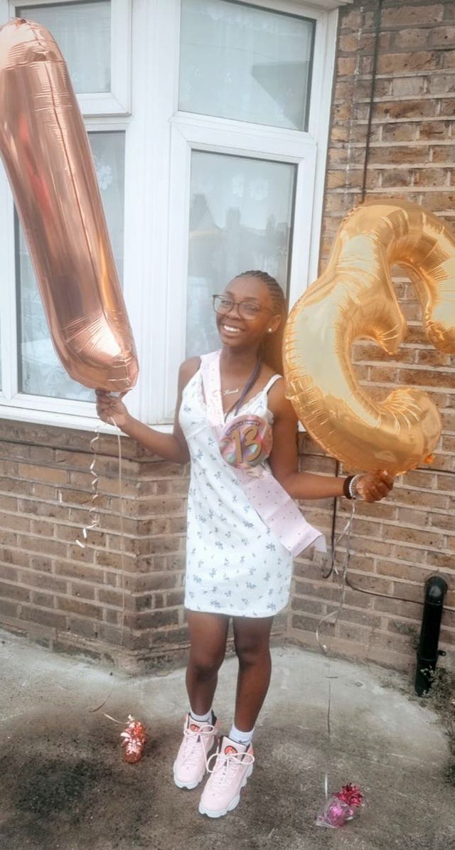 Hannah Jacobs holding balloons which take the shape of the number 13