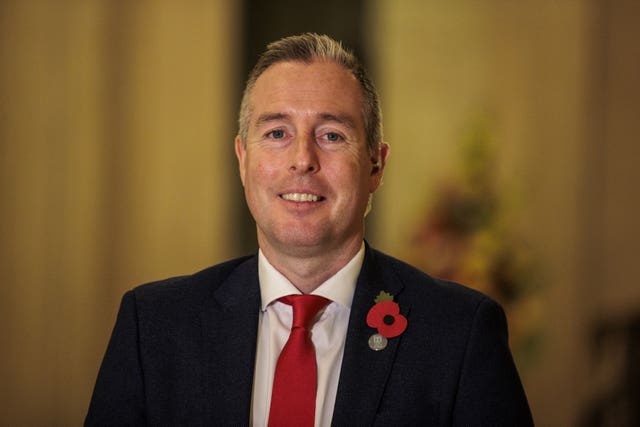 Head and shoulders photo of Paul Givan, dressed in a suit jacket and tie, smiling