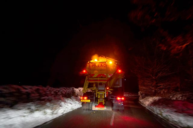 A gritter salts the road in the night