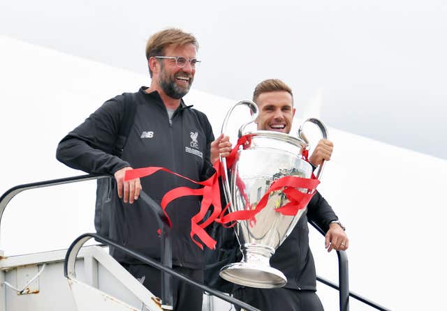 Klopp and Henderson emerge from the plane with the silverware