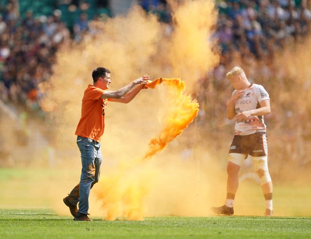 A Just Stop Oil protester throws orange powder on the pitch at Twickenham