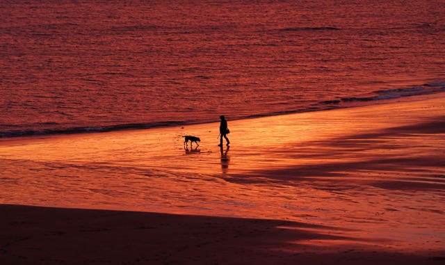 A person walks along Tynemouth Beach as the sun rises in North Shields 