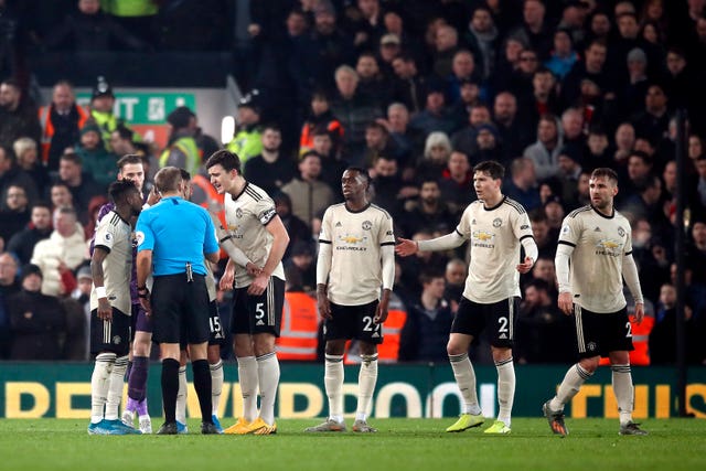 Manchester United players protest to referee Craig Pawson, third left, during their loss to Liverpool