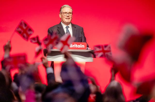 People wave flags as Prime Minister Sir Keir Starmer delivers his keynote speech during the Labour party conference 