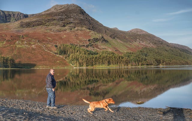 A man walking his dog in Cumbria (Owen Humphreys/PA)