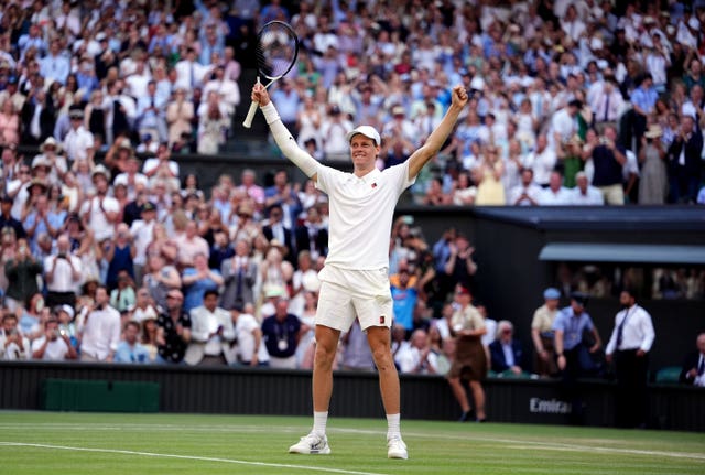 Jannik Sinner stands with his arms aloft in celebration