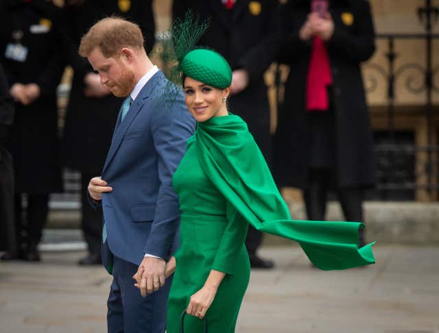 Harry with his head bowed and and Meghan smiling at the camera as they arrive at the Commonwealth Day Service in 2020