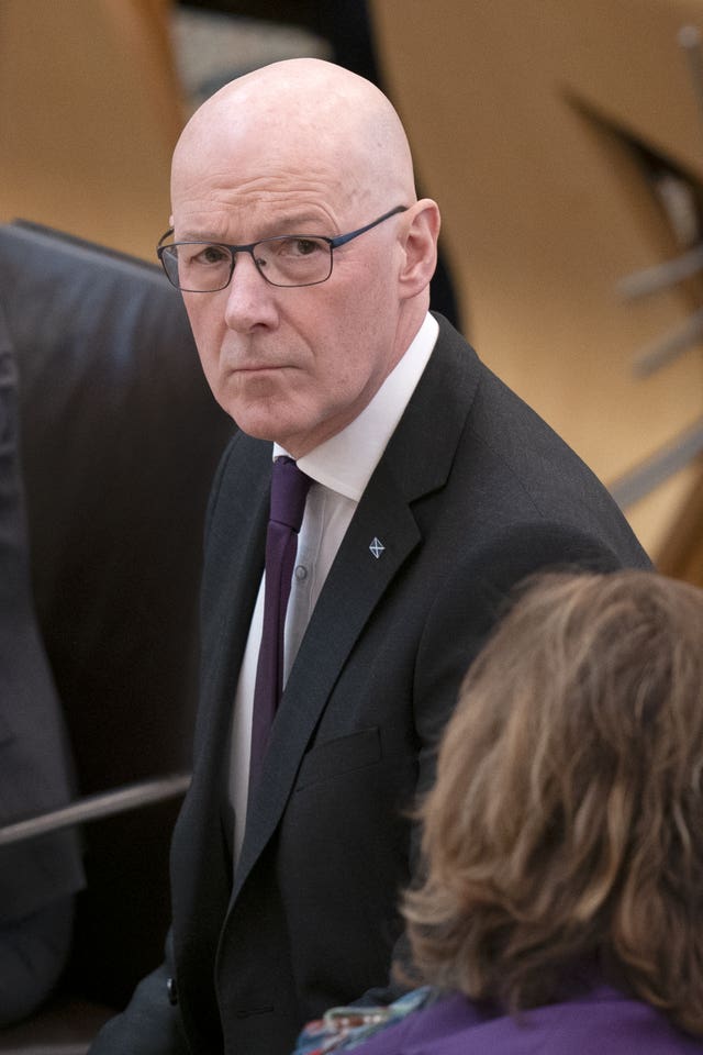 John Swinney seated in the Holyrood chamber