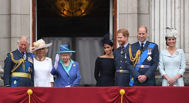 Harry and Meghah look at the Queen as she waves from the palace balcony during the centenary celebrations of the Royal Air Force