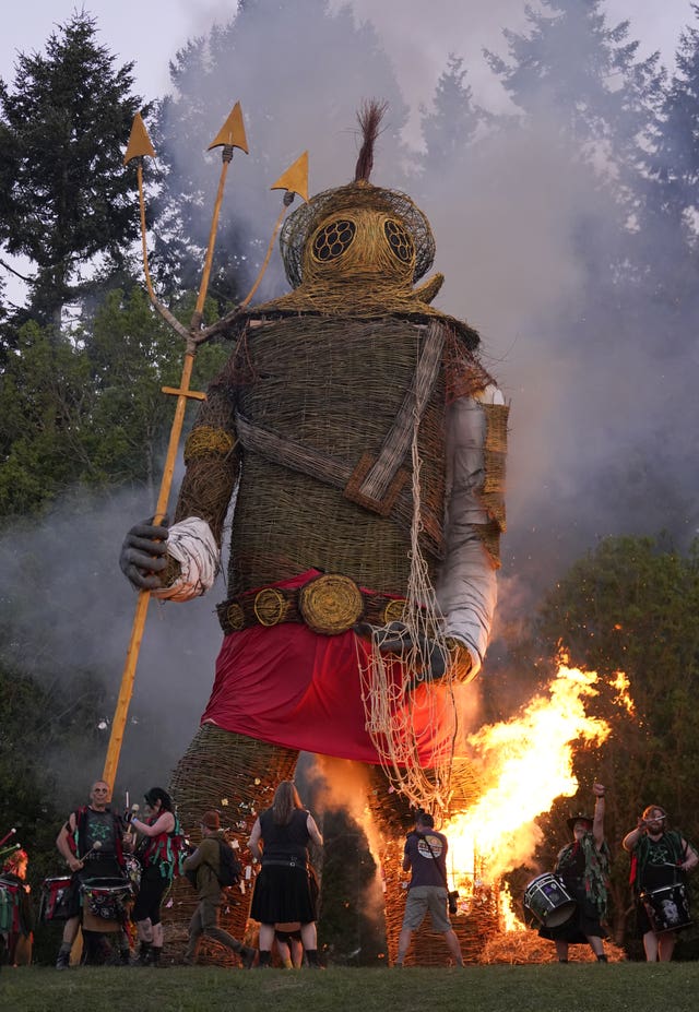 Members of the Pentacle Drummers perform in front of a burning wicker man at the Beltain Celtic Fire Festival