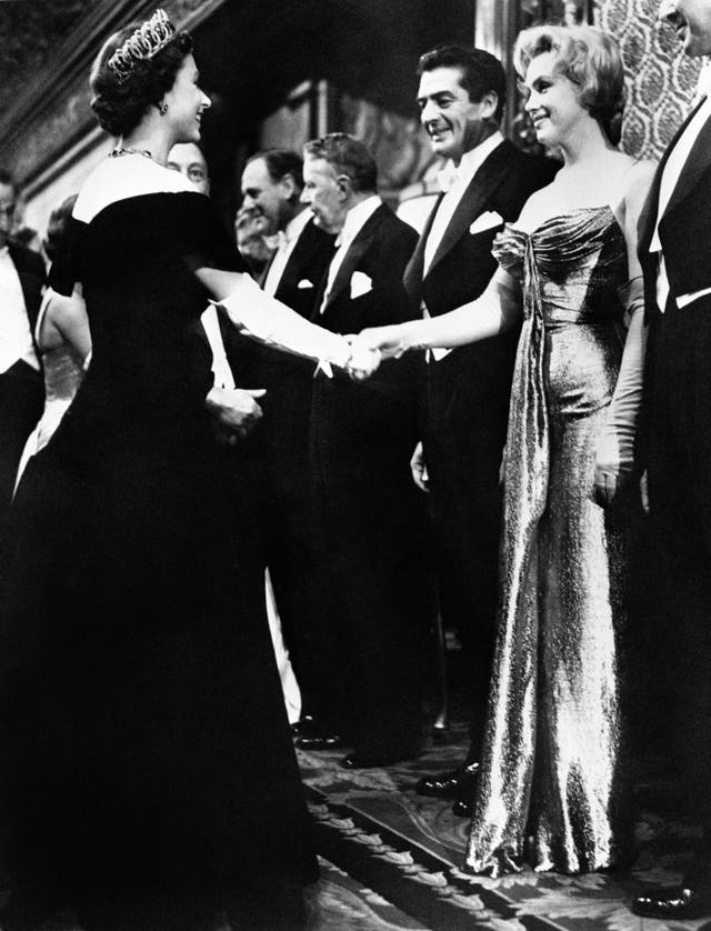 Marilyn Monroe, as part of a line-up, shaking hands with the late Queen