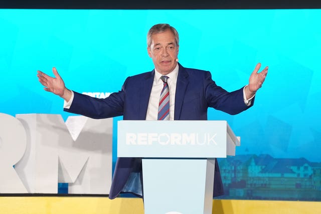 Nigel Farage with his arms aloft while speaking from a Reform UK lectern