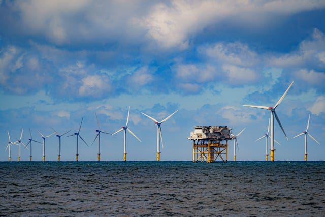 A row of offshore wind turbines line the sea's horizon