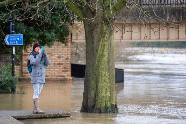 A woman takes a photo of flooding in Bedford 