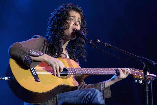 Katie Melua playing the guitar and singing into a microphone