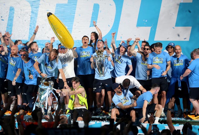 Manchester City players celebrate on stage with their trophies