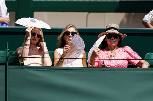 Spectators use fans to cool down