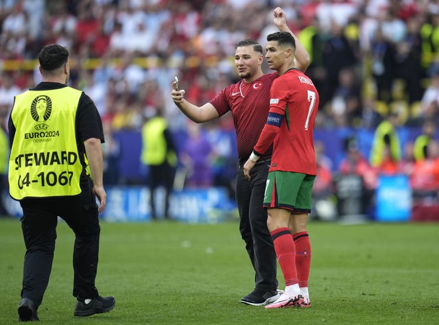 A pitch invader attempts to get a photo with Portugal’s Cristiano Ronaldo before security intervene