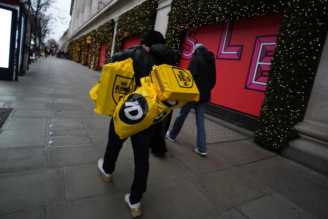 People walking along a high street carrying JD Sports bags