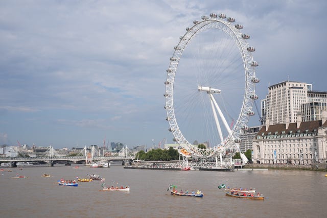 A group of small boats pass the London Eye wheel