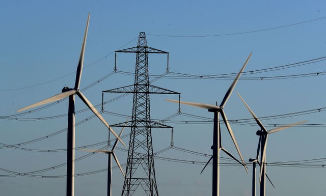 Wind turbines standing alongside electricity pylons