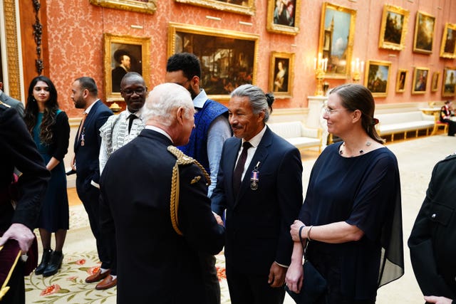 The King presents the Humanitarian Medal to Nicholas Cairns during a medal presentation at Buckingham Palace, London