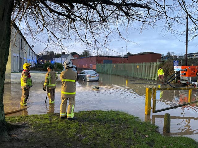 Firefighters pump water from a flooded road