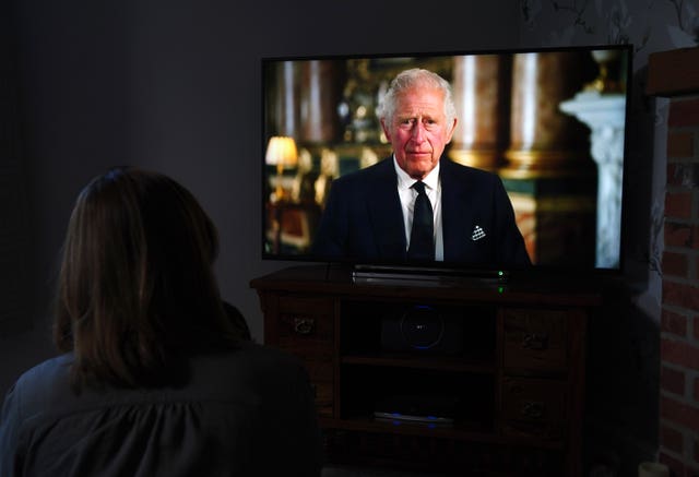 A child watches a TV screen showing the King making his first televised address to the nation as the new monarch in September 2022