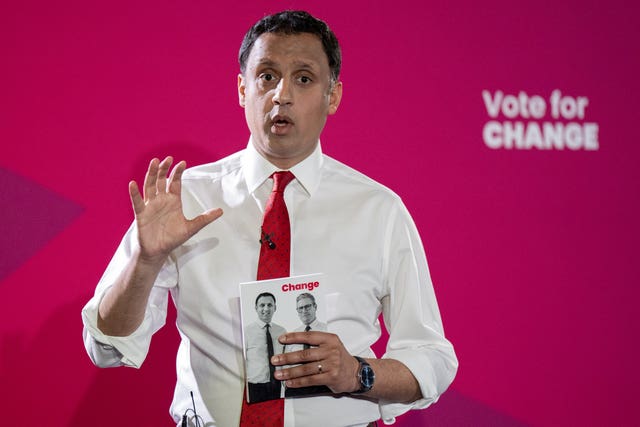 Anas Sarwar, with one hand raised, speaking in front of Labour 'vote for change' signage