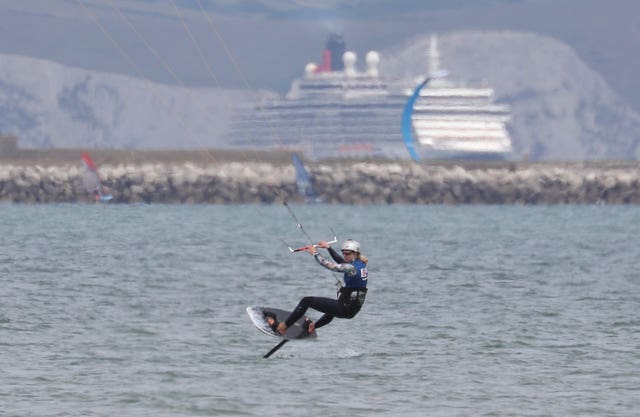 Ellie Aldridge kitesurfing with a cruise ship in the distant background. 