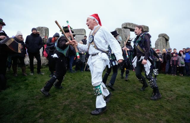 Morris dancers perform in front of the stones as people take part in the winter solstice celebrations during sunrise at Stonehenge 