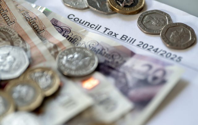 Coins and bank notes lying on a piece of paper with the words 'council tax bill' on it
