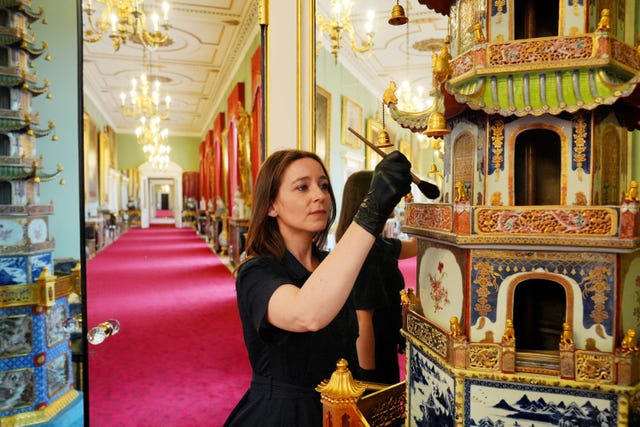 A staff member brushing an ornament in the Buckingham Palace East Wing Principal Corridor