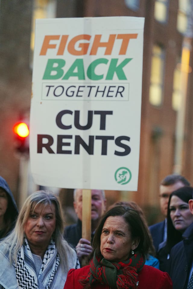 Mary Lou McDonald (right) standing with protesters including a man behind her holding a placard which reads 'Fight back together, cut rents'