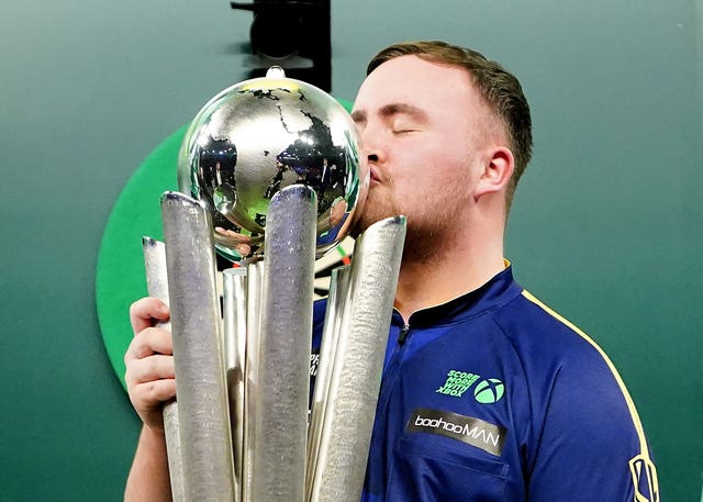 Luke Littler kisses the Sid Waddell Trophy