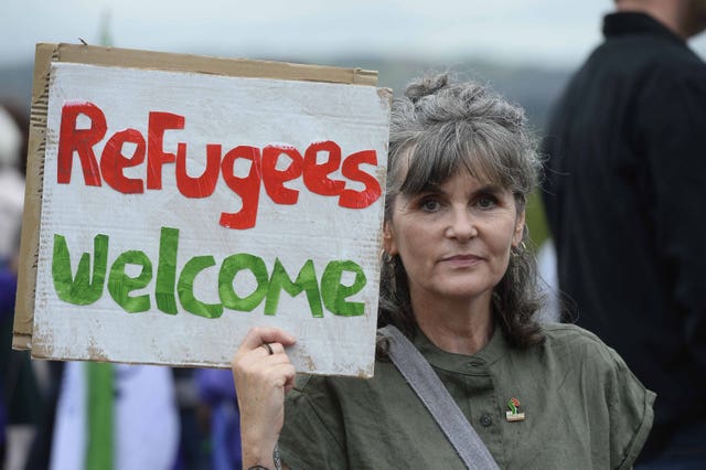 A woman holds up a sign saying Refugees Welcome during a protest by unions at Stormont