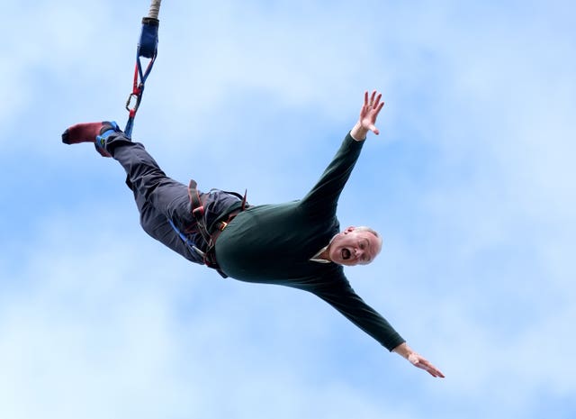 Sir Ed Davey screams and holds his arms out wide as he takes part in a bungee jump 